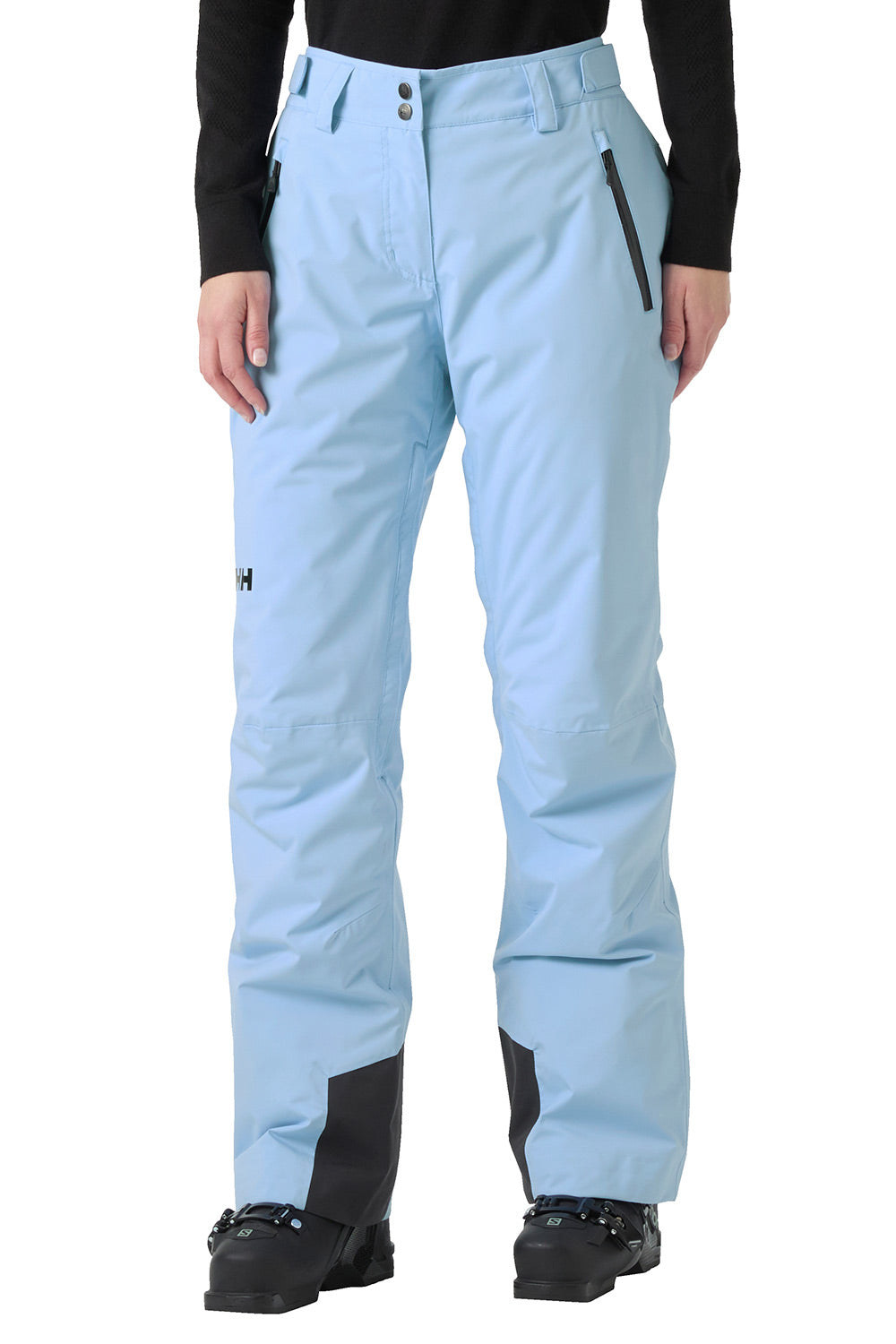 Light blue snow pants with black knee panels and a black zipper pocket, shown on a model wearing a black long-sleeve top and black ski boots against a white background.