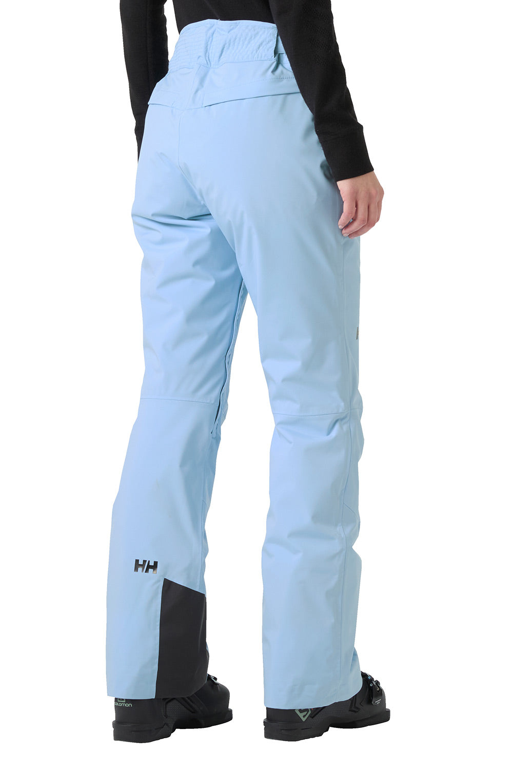 Light blue ski pants with black contrast panels at the lower legs, shown from the back on a model wearing a black long-sleeve top and black ski boots against a white background.