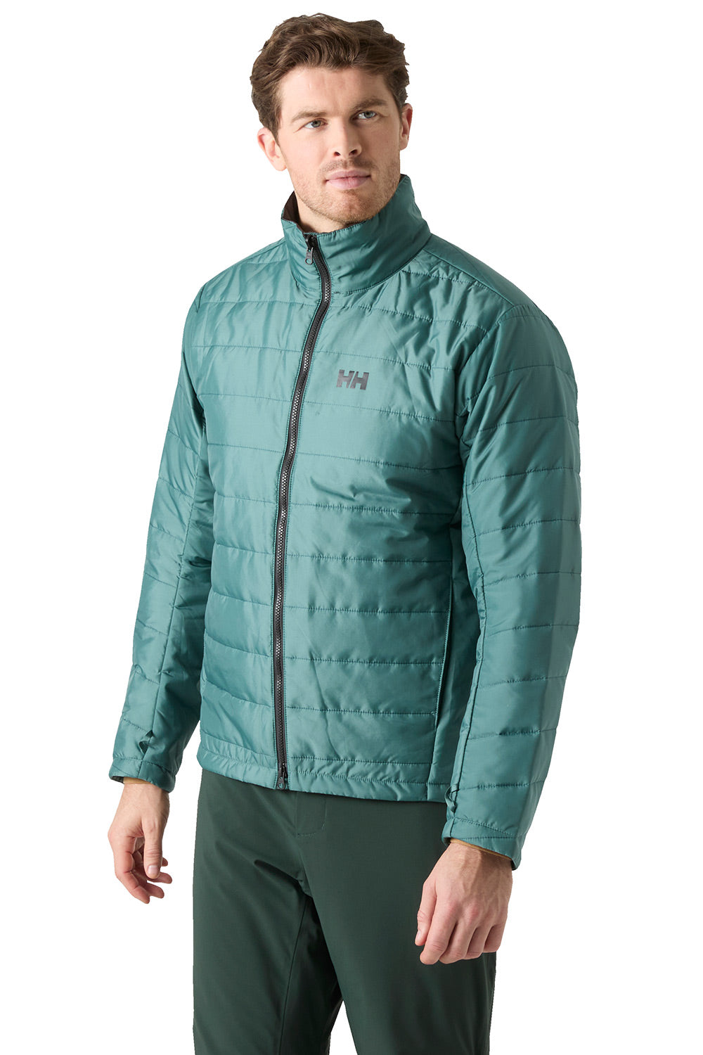 A man wearing a teal green quilted puffer jacket with a black zipper and a small gray logo on the left chest, paired with dark green pants, against a plain white background.