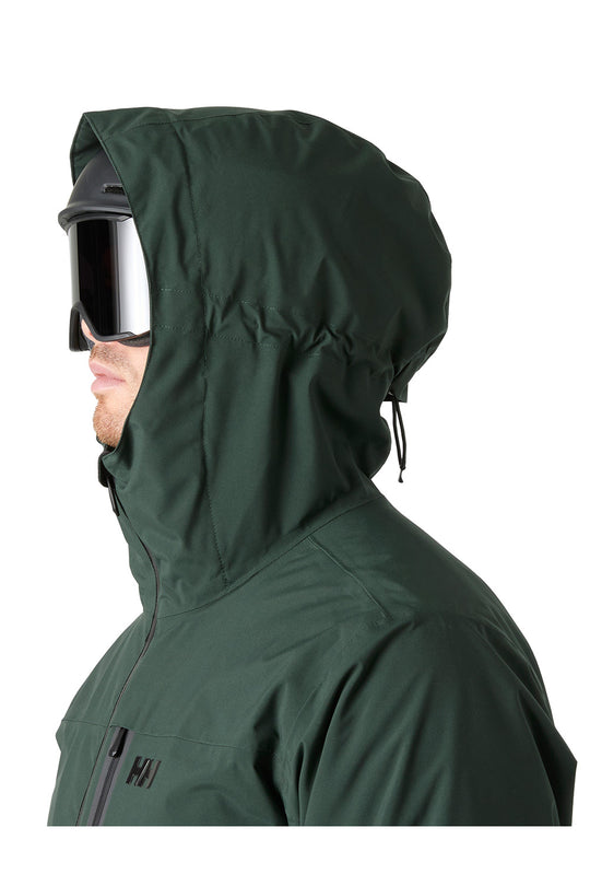 A side profile of a person wearing a dark forest green hooded ski jacket and black ski goggles against a solid white background.
