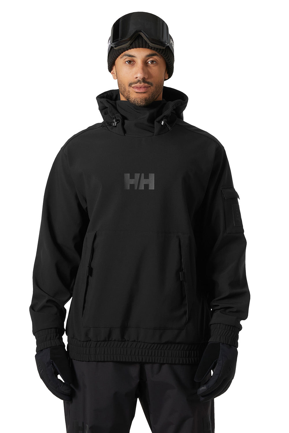 A man wearing a black Helly Hansen hooded jacket with a dark gray HH logo on the chest, black beanie with goggles, and black gloves, shown against a plain white background.