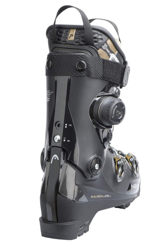 A black ski boot with a dial closure system and gold accents, shown from a three-quarters angle on a white background.