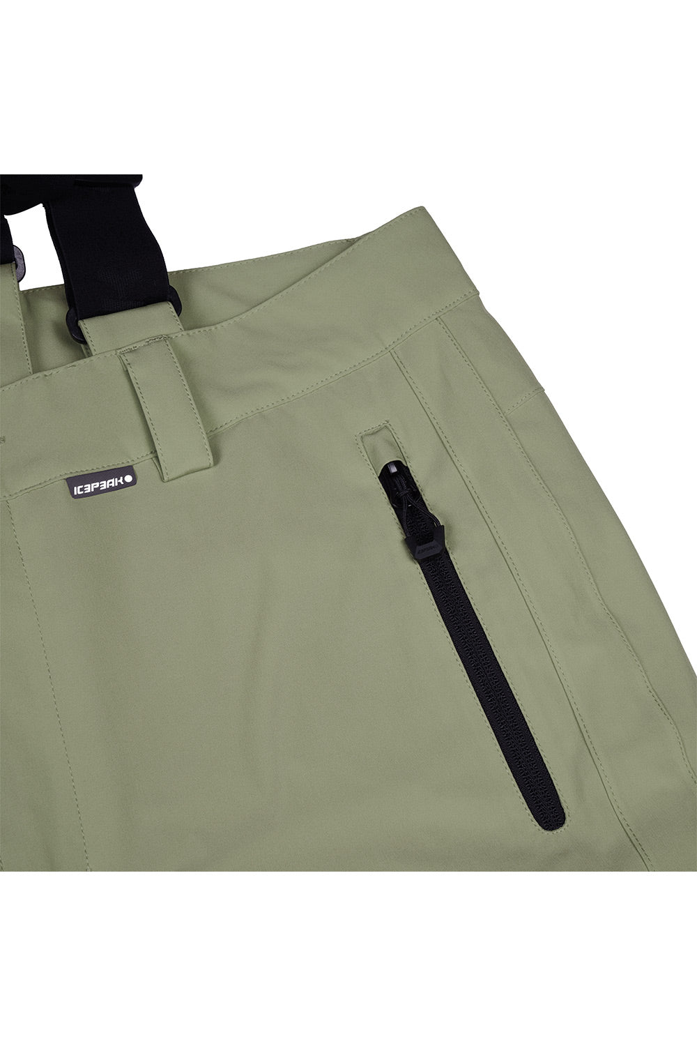 Close-up of olive green outdoor pants with a black zipper pocket and a small black brand tag reading GORUCKI.