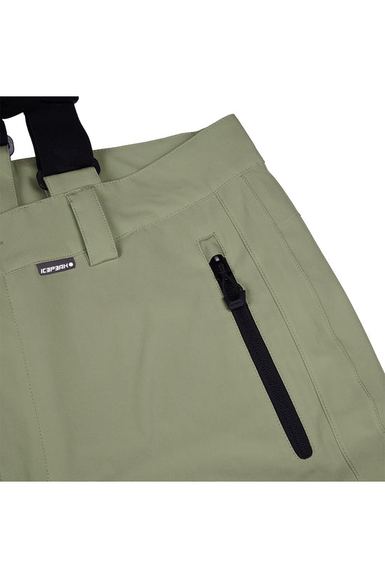 Close-up of olive green outdoor pants with a black zipper pocket and a small black brand tag reading GORUCKI.