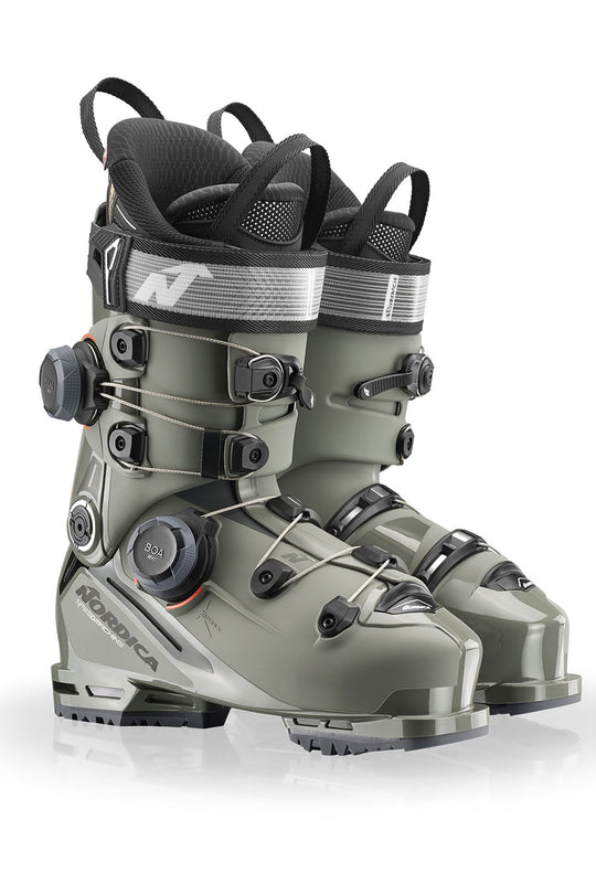 Pair of green ski boots with black straps on a white background