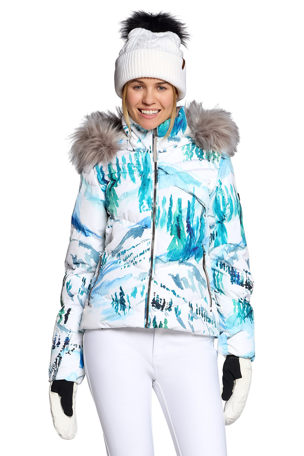 A woman wearing a white winter jacket with a blue and green mountain landscape print, a white knit beanie with a black pom-pom, white ski pants, and white gloves with black palms, posed against a solid white background.