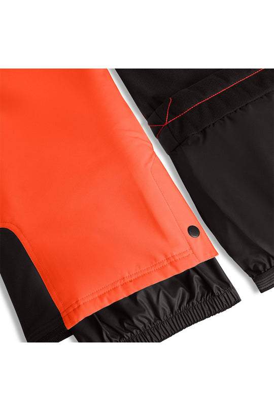 Close-up of a pair of pants showing a bright orange panel and black fabric with red contrast stitching and elastic cuffs.
