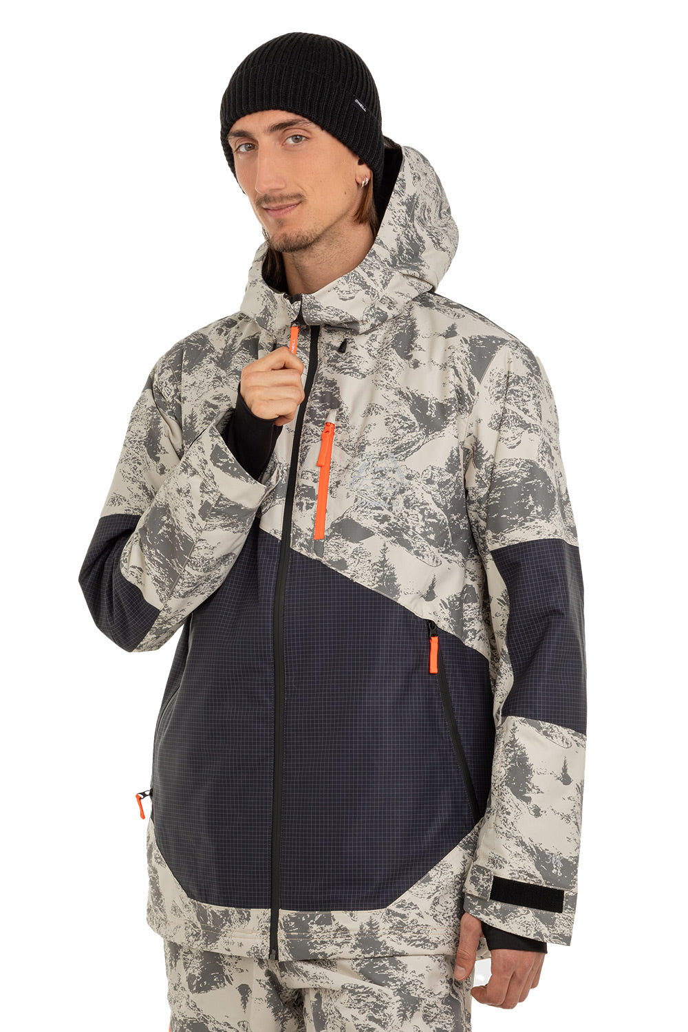 A man wearing a ski jacket with a gray and white mountain camouflage pattern and dark navy blue panels, paired with matching camouflage pants and a black beanie, against a plain white background.