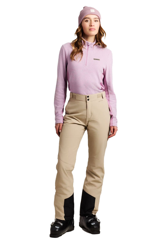 Woman wearing a pink top, beige pants, and black boots on a white background