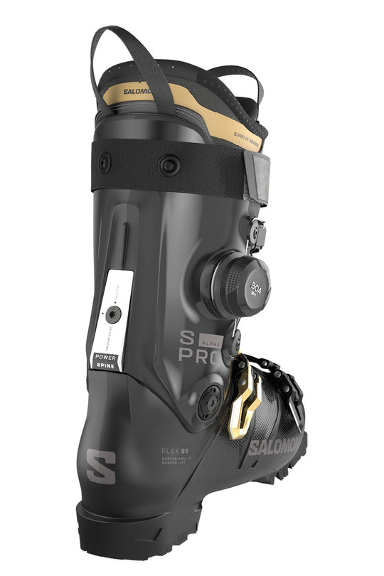 Black ski boot with gold accents on a white background