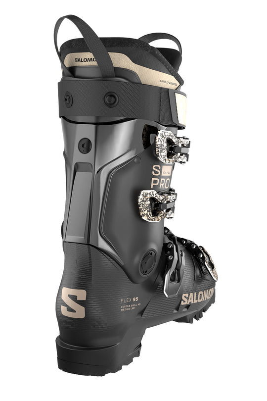 Salomon ski boot in black with beige branding and silver buckle hardware, shown from a side profile on a white background.