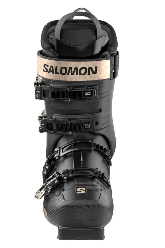A Salomon ski boot in black with a beige logo band on the cuff, shown from a front-facing perspective against a white background.