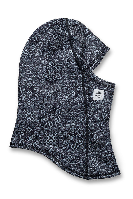 A dark gray and white patterned balaclava face covering with a small white brand label on the side, displayed on a clean white background.