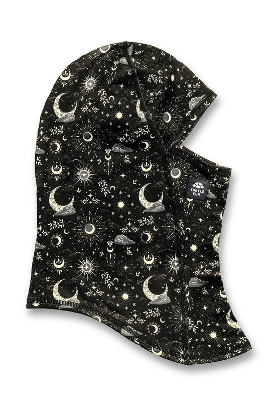 A black hooded face covering with an all-over celestial print of white and light beige crescent moons, stars, and suns, shown on a plain white background.