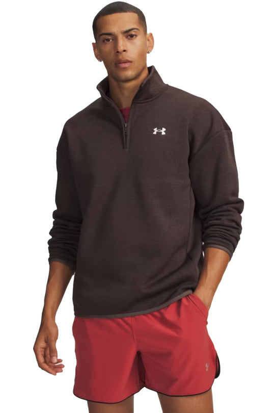 A man wearing a dark brown Under Armour quarter-zip pullover and red athletic shorts, standing against a plain white background.