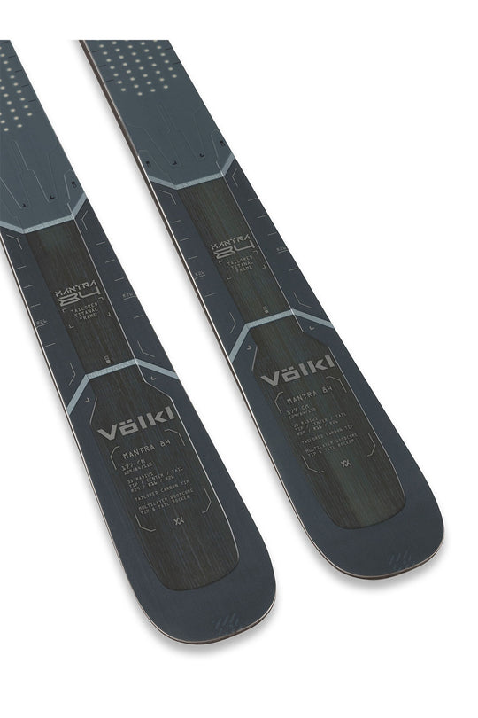 Two Volkl skis shown from the bottom side, featuring a dark gray and black design with light gray geometric accents and white branding, set against a plain white background.