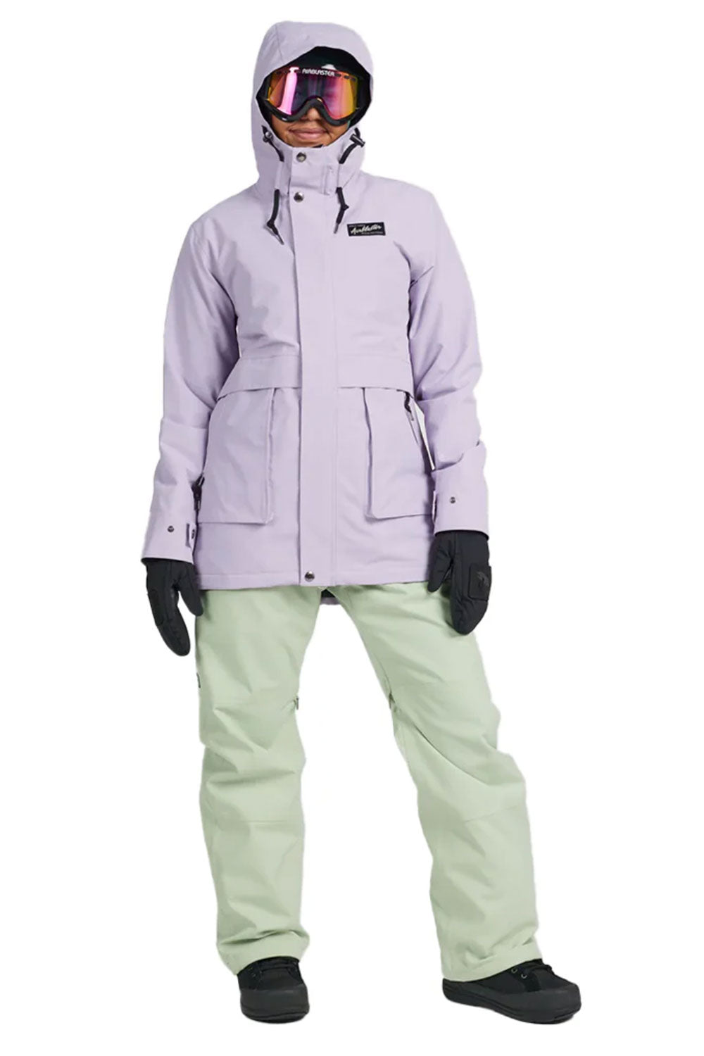 Person wearing a light purple snow jacket and light green pants with black gloves and goggles on a white background