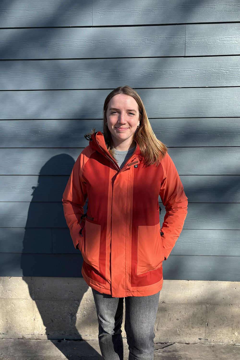 Person wearing an orange jacket standing against a blue wall