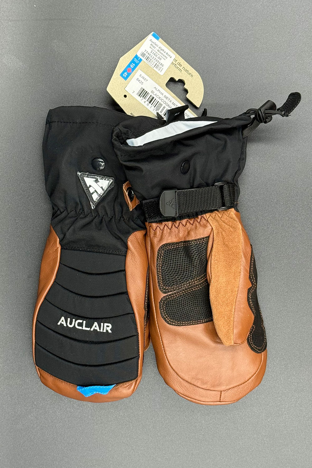 Pair of black and brown Auclair mittens on a gray background