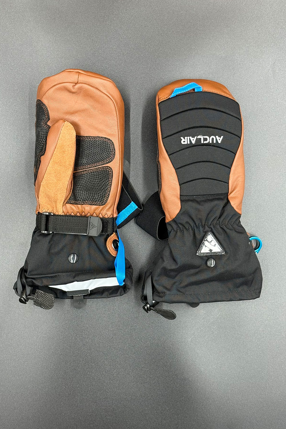 Pair of brown and black gloves with visible brand logo on a gray background