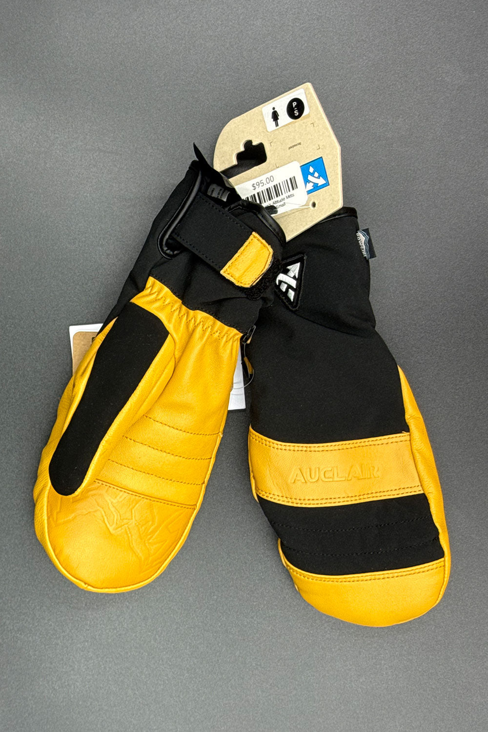 Pair of yellow and black mittens with a brand tag on a gray background