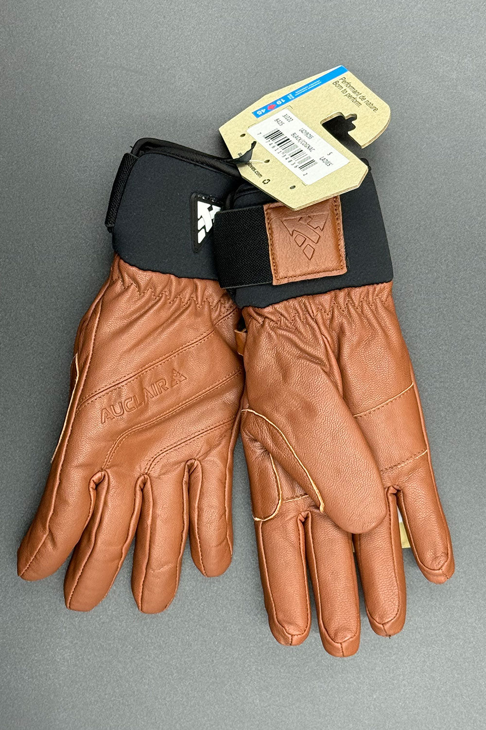 Brown leather gloves with a tag on a gray background