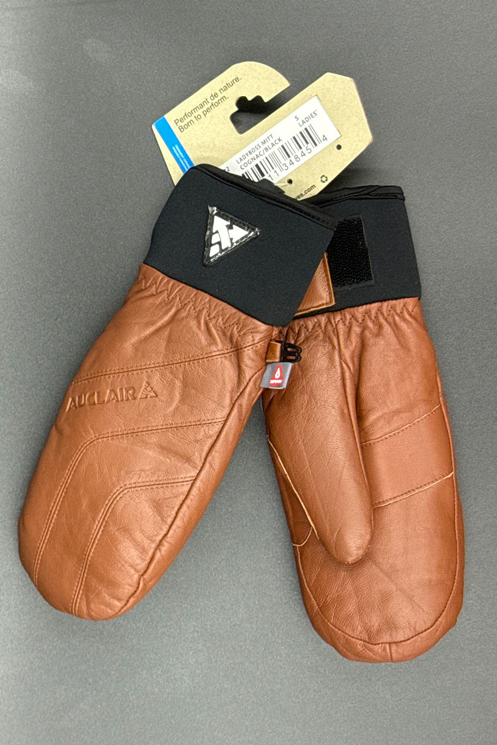 Brown leather mittens with a brand tag on a gray background