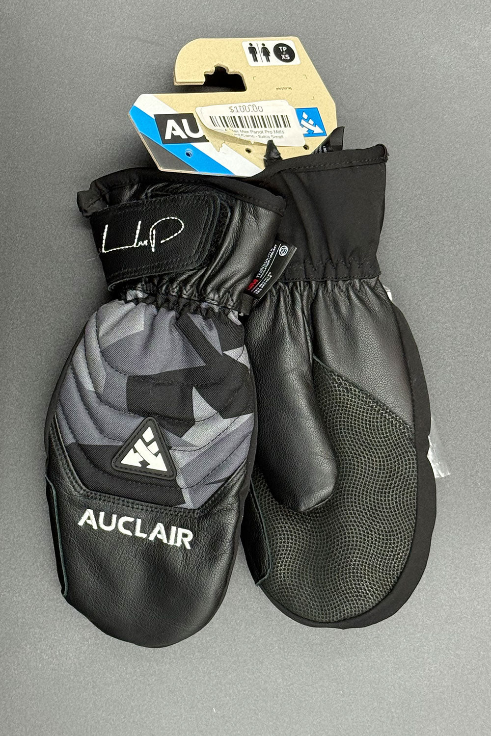 Pair of Auclair mittens with a visible brand tag on a gray background