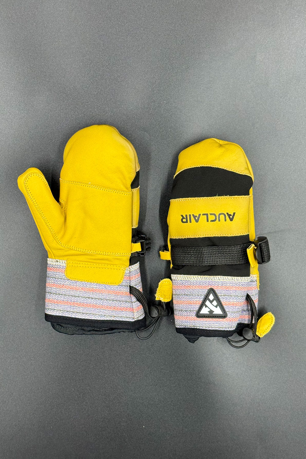 Yellow ski mittens with a visible brand logo on a gray background