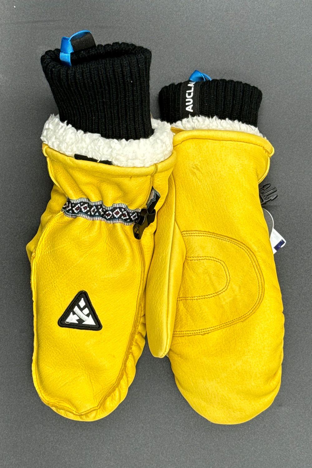 Yellow mittens with black and white accents on a gray background