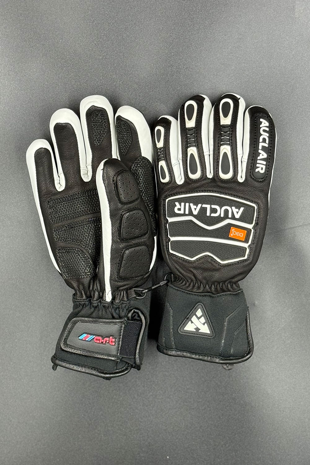Pair of black and white gloves with visible branding on a gray background