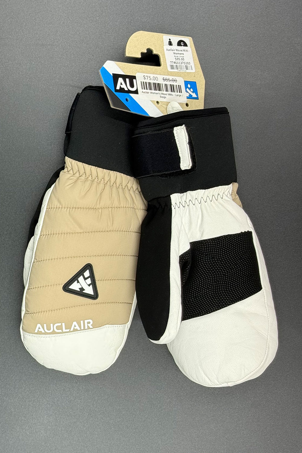Pair of beige and black mittens with a visible brand tag on a gray background