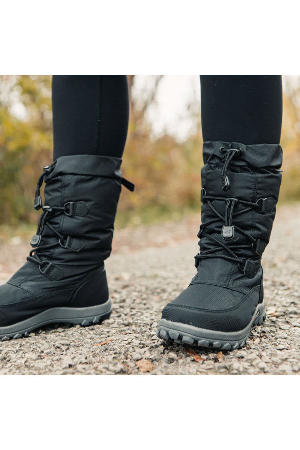 Black winter boots worn on a blurred natural background