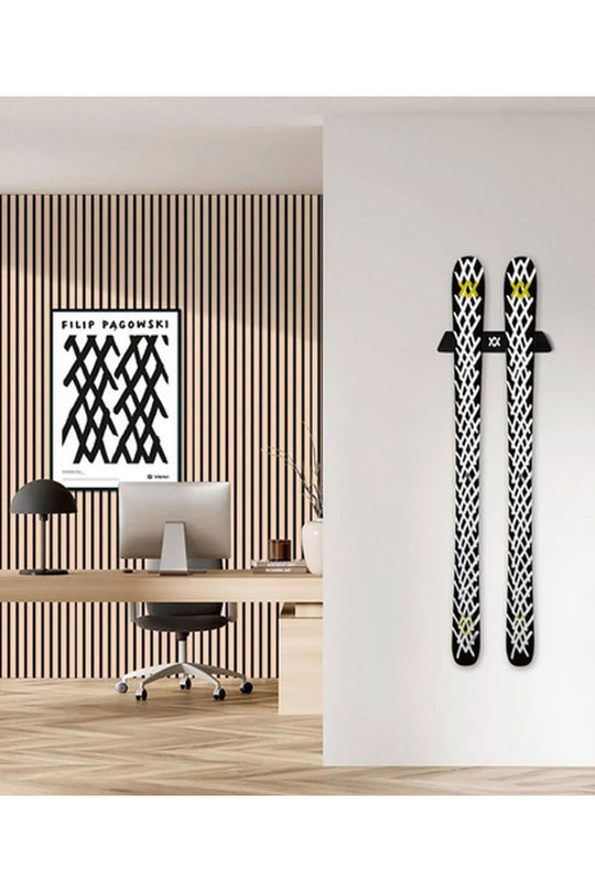 Two skis with black and white patterns on a wall next to a modern office setup.