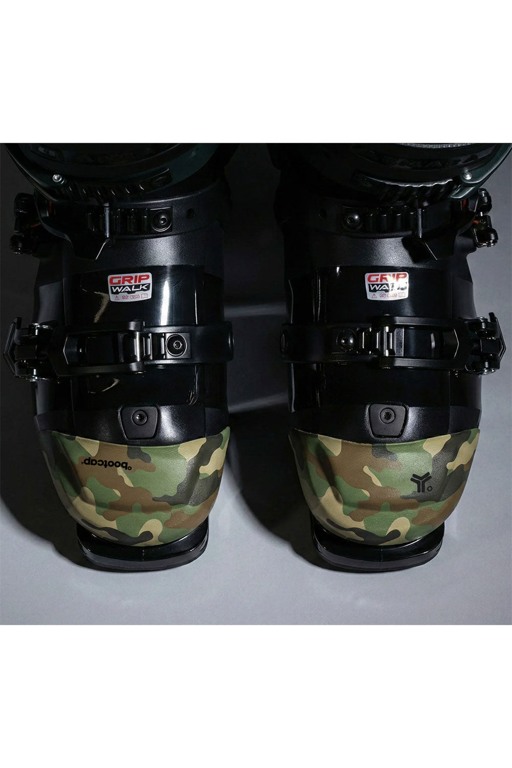 Close-up of ski boots with camouflage design and visible brand logos on a white background