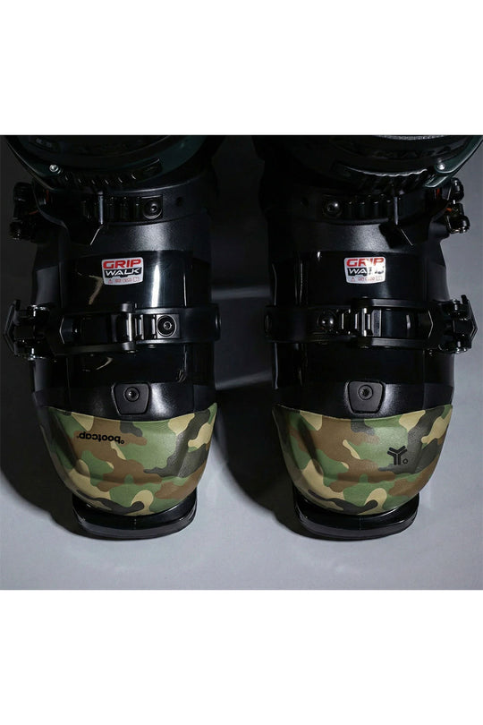 Close-up of ski boots with camouflage design and visible brand logos on a white background