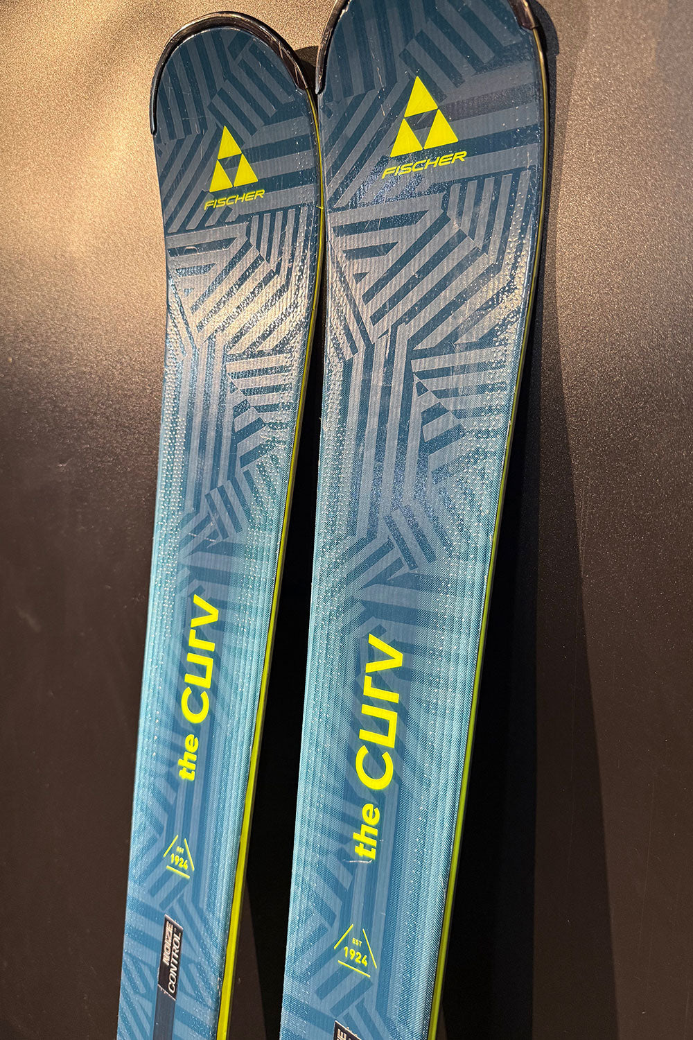 Pair of blue Fischer skis with yellow text on a dark background
