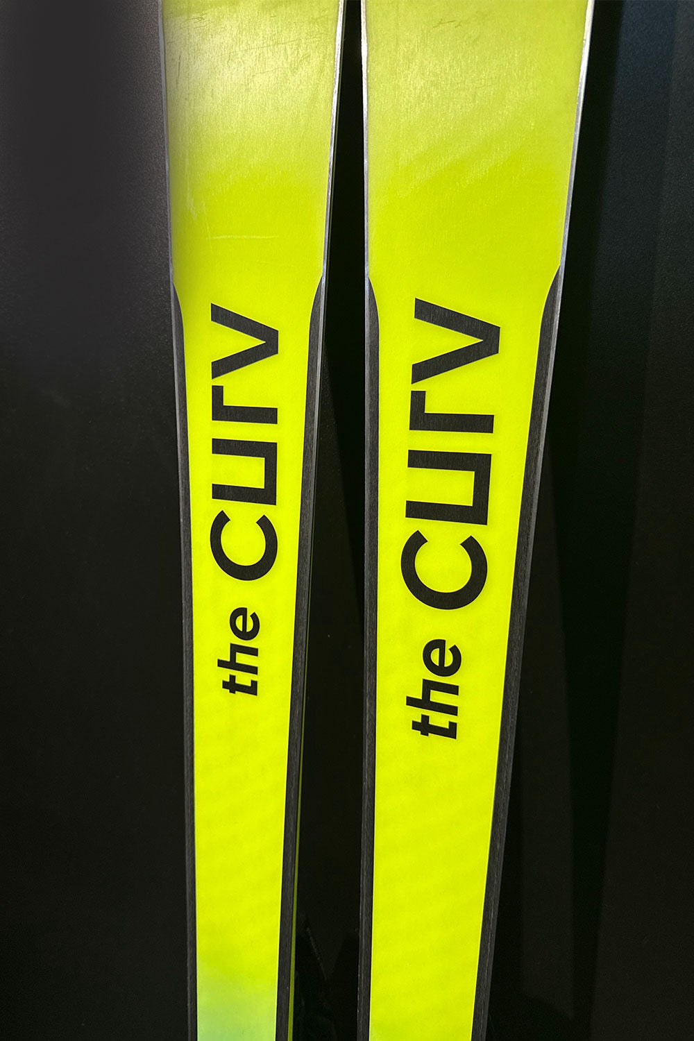 Two yellow skis with 'the CURV' branding on a black background