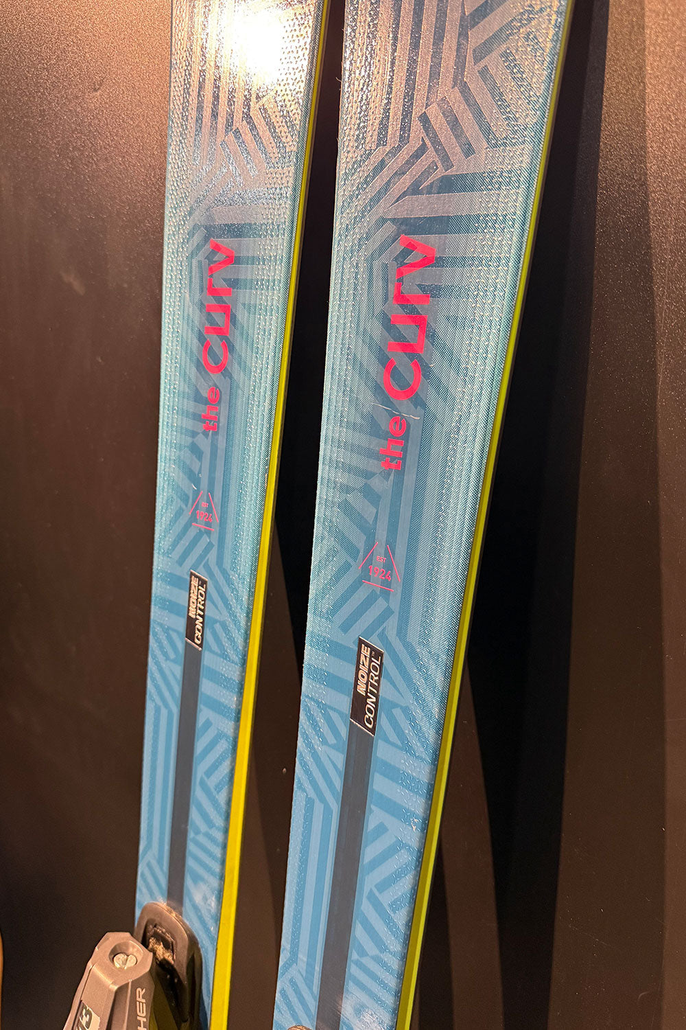 Two blue skis with red branding on a dark background