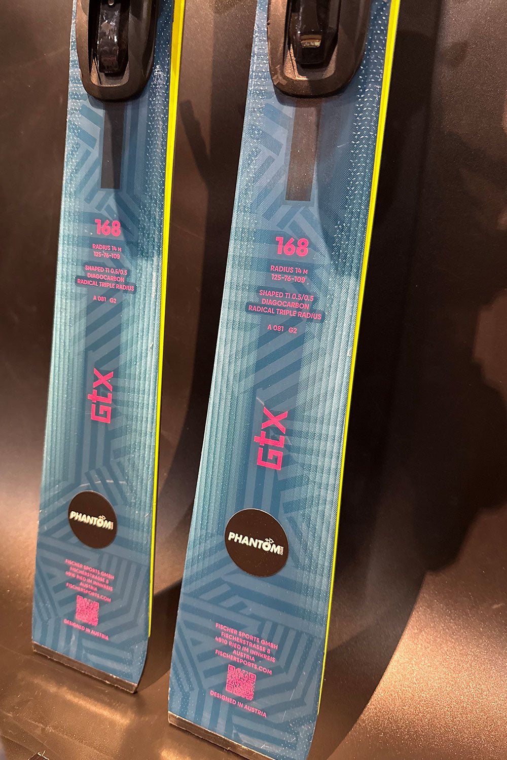 Two pairs of skis with bindings on a reflective surface