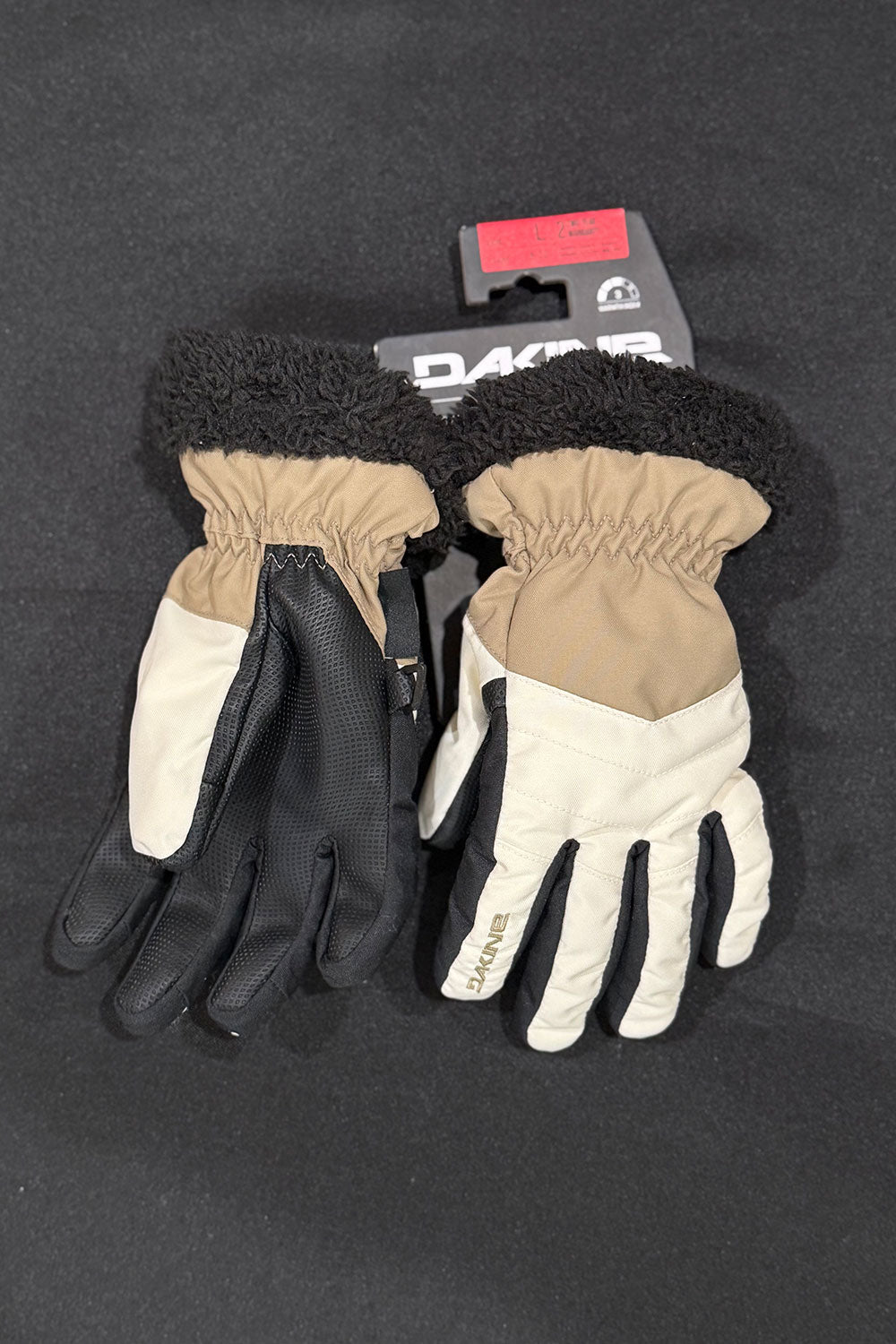Pair of black and beige gloves with a brand tag on a dark background