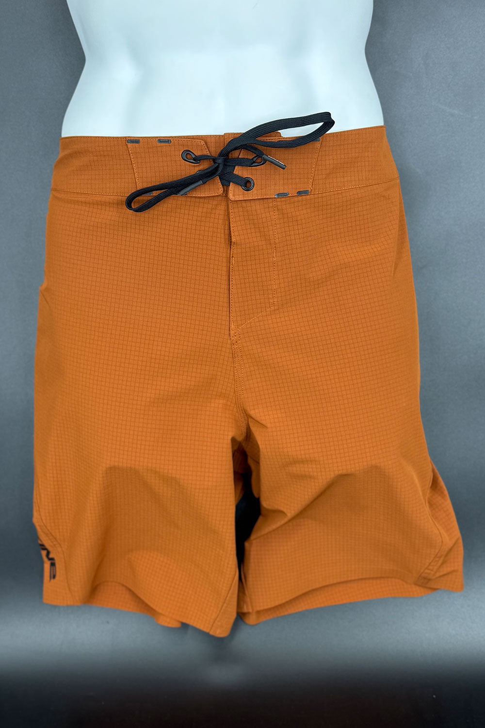 Orange shorts with a black drawstring on a gray background