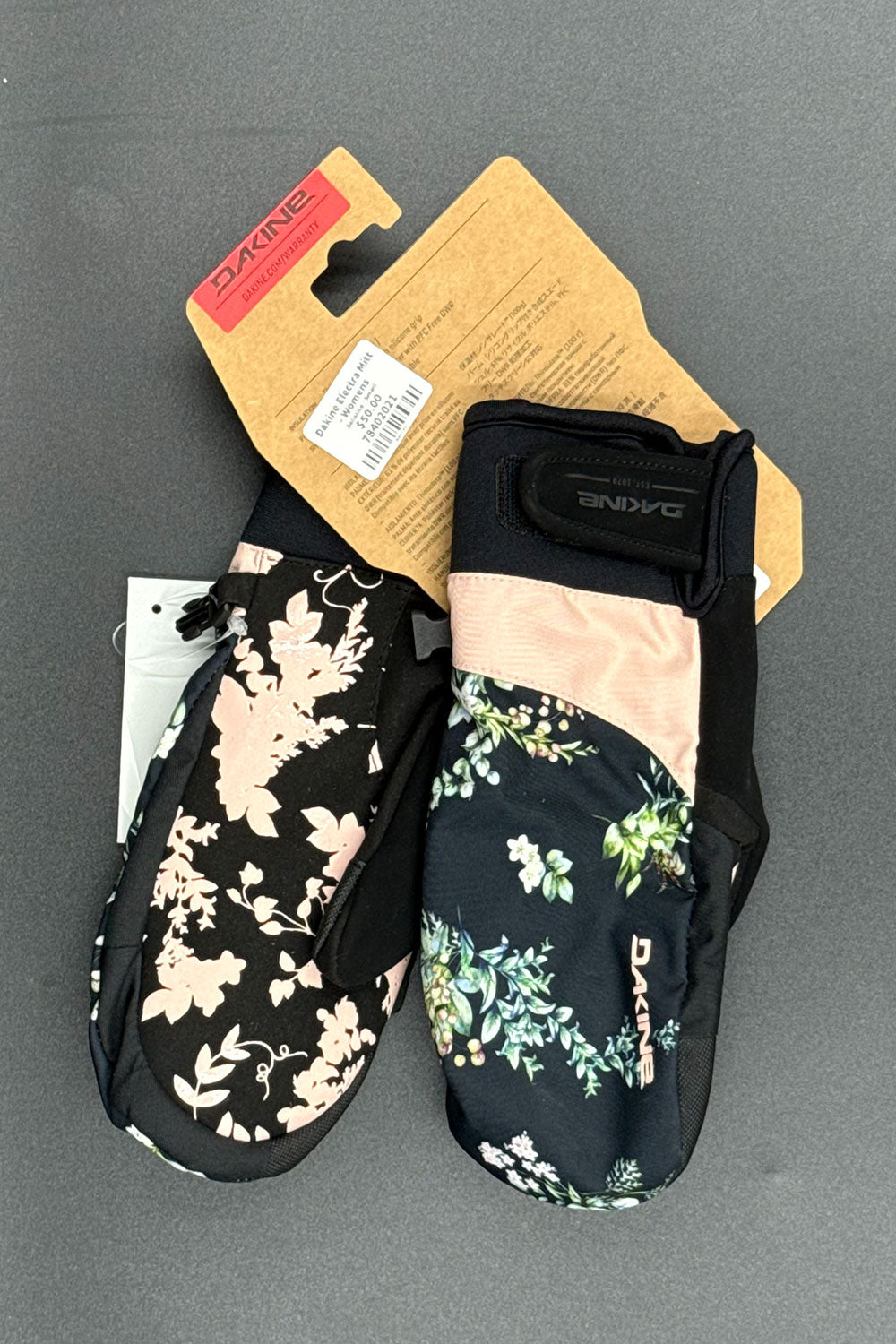 Floral-patterned mittens with Dakine branding on a gray background