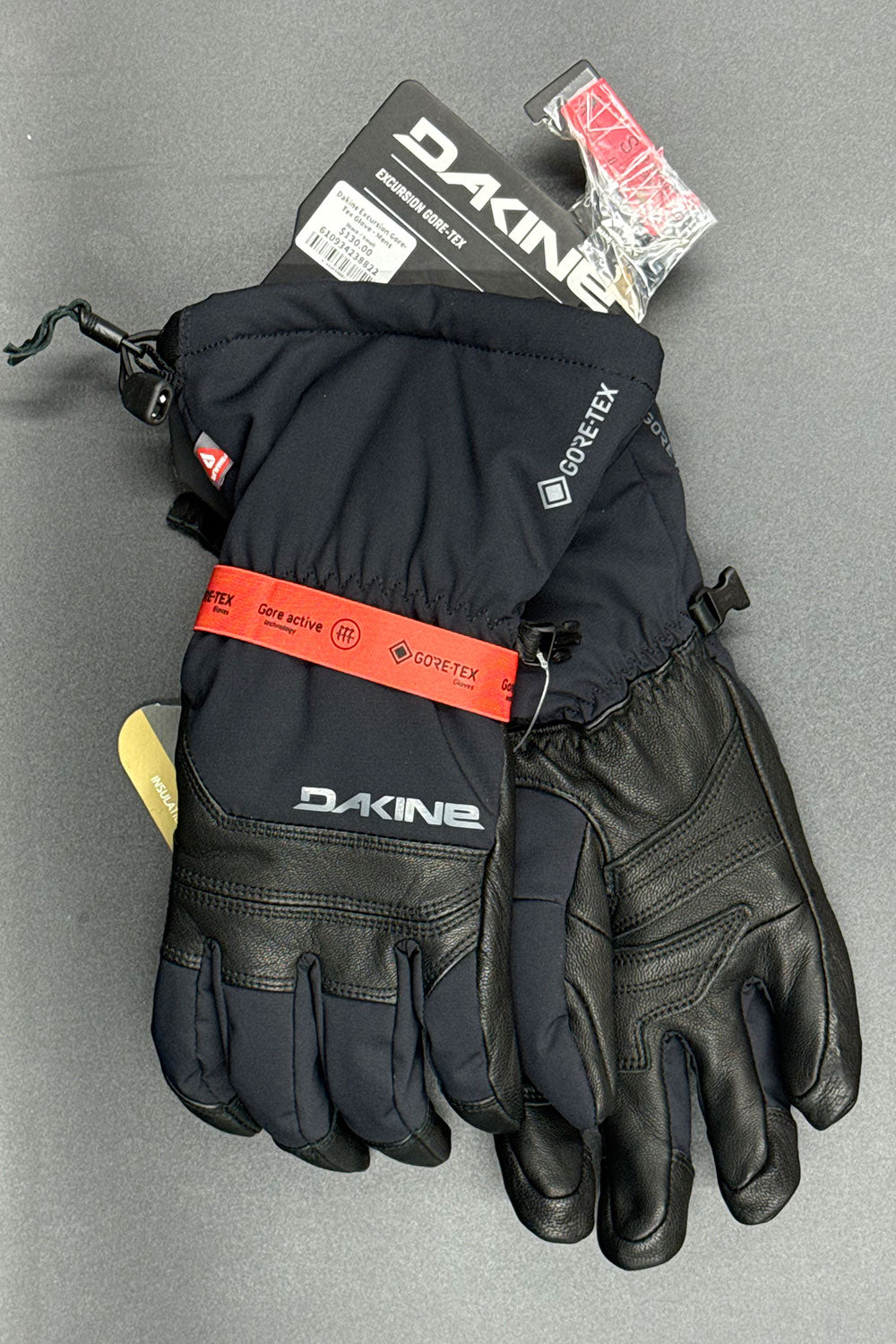 Pair of black gloves with Dakine branding on a gray background