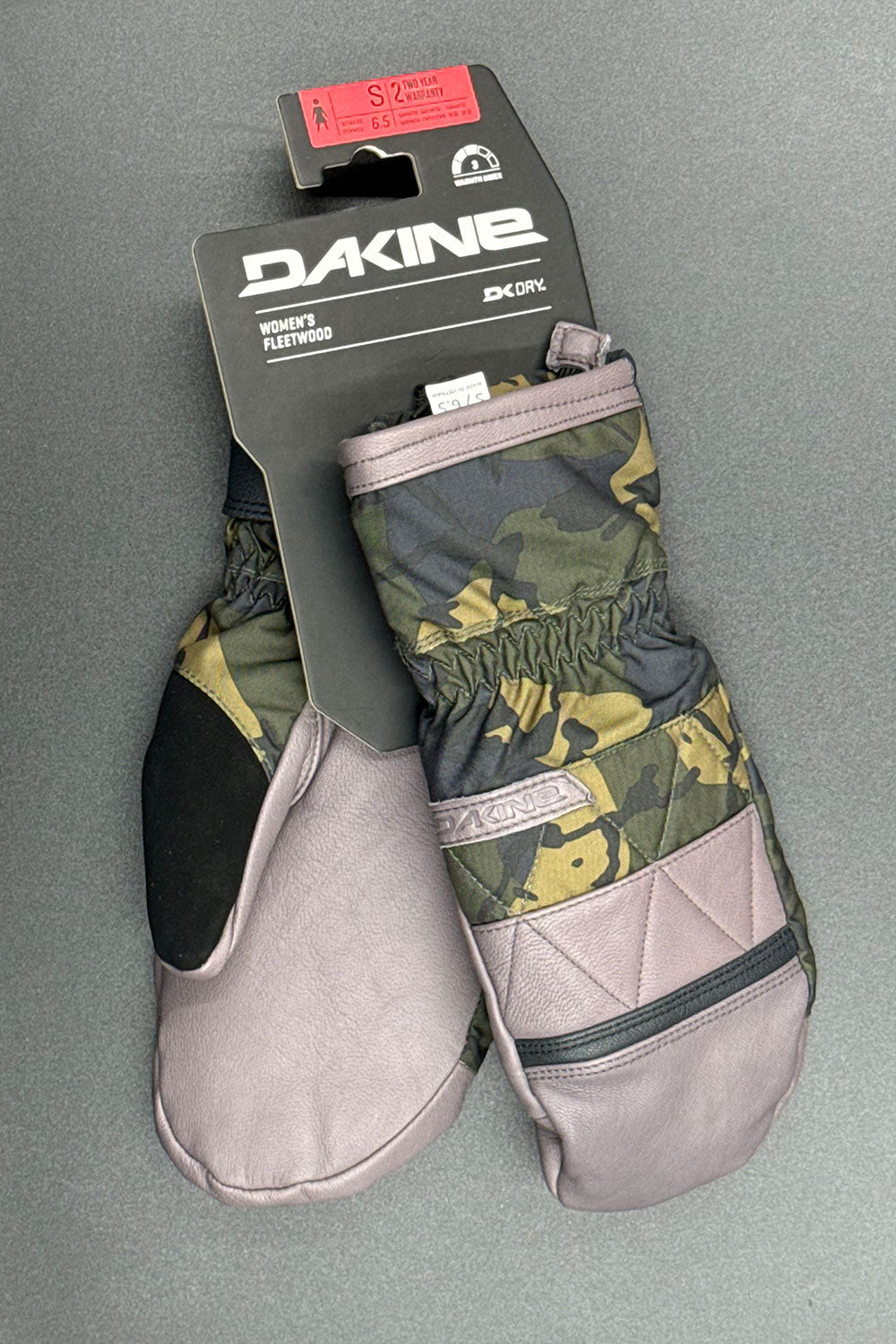 Pair of gloves with camouflage pattern and quilted palm, branded 'Dakine', on a gray background.