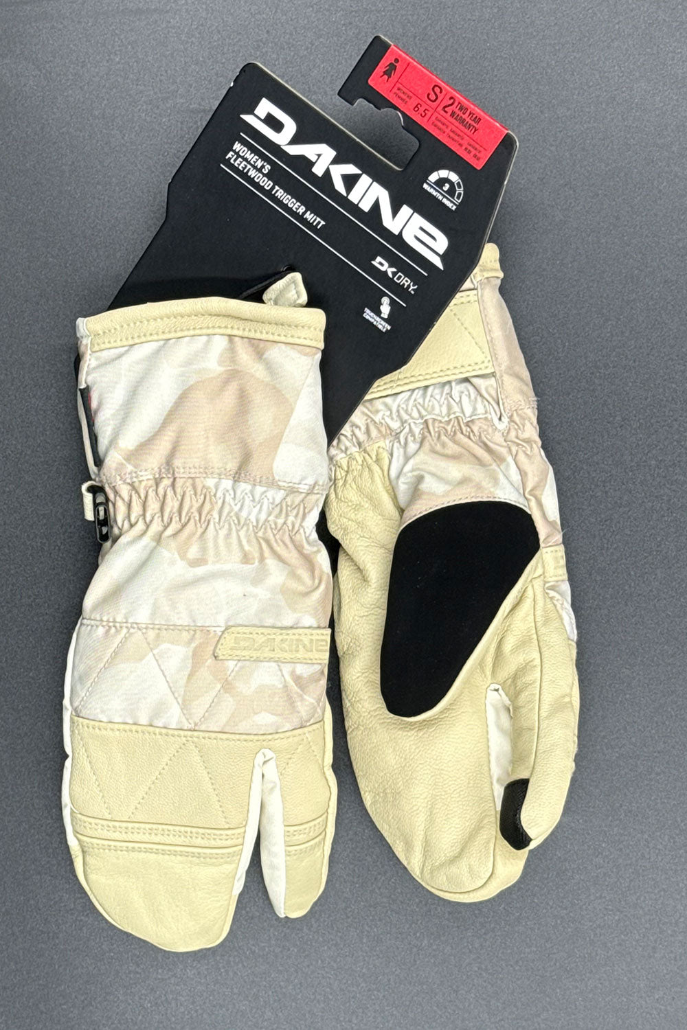 Pair of beige gloves with a Dakine brand label on a gray background