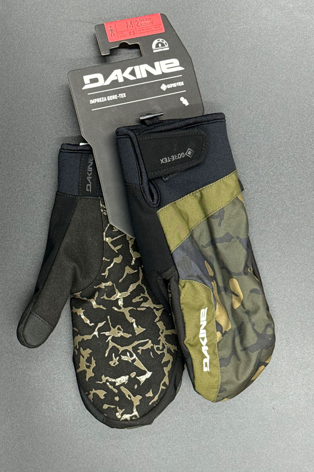 Camouflage mittens with Dakine packaging on a gray background