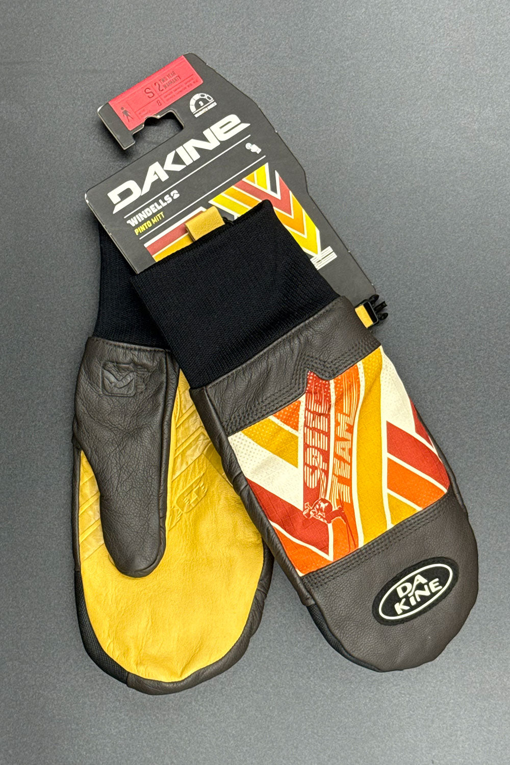 Pair of Dakine mittens with colorful design on a gray background