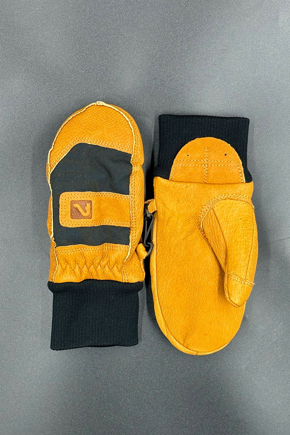 Pair of leather mittens with black accents on a gray background