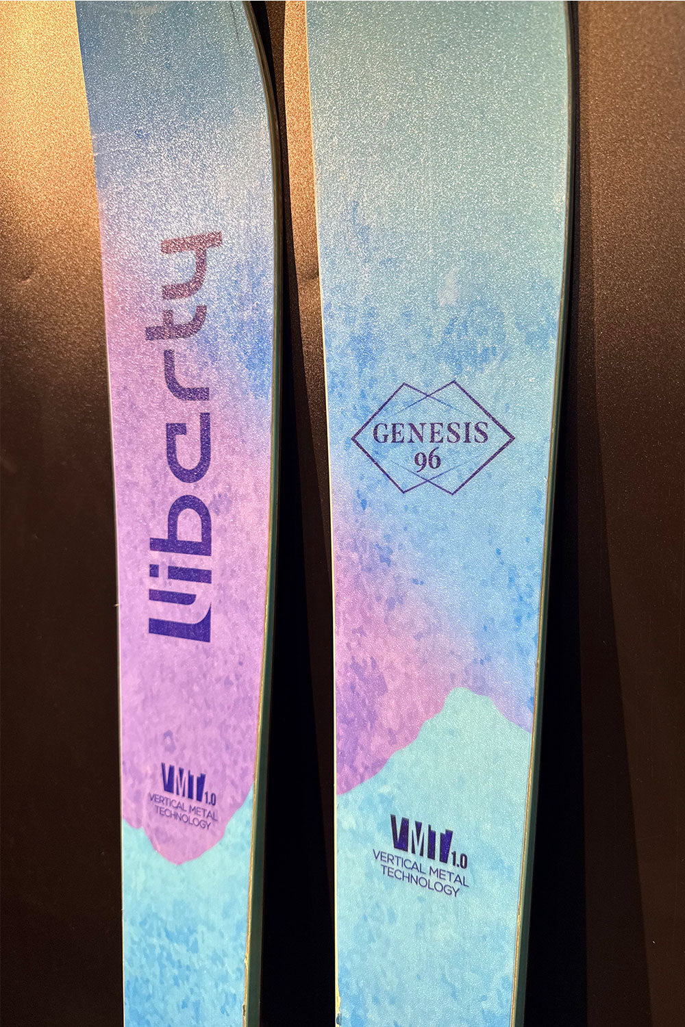 Two skis with 'Liberty' and 'Genesis' branding on a dark background